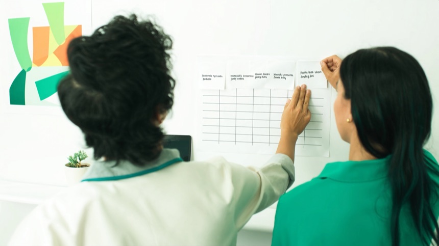 Dos compañeras montando un flujo en la pared tras organizar los contactos del negocio en el CRM