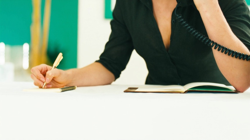 Recepcionista anotando un recado en papel para no perder mensajes de WhatsApp para empresas